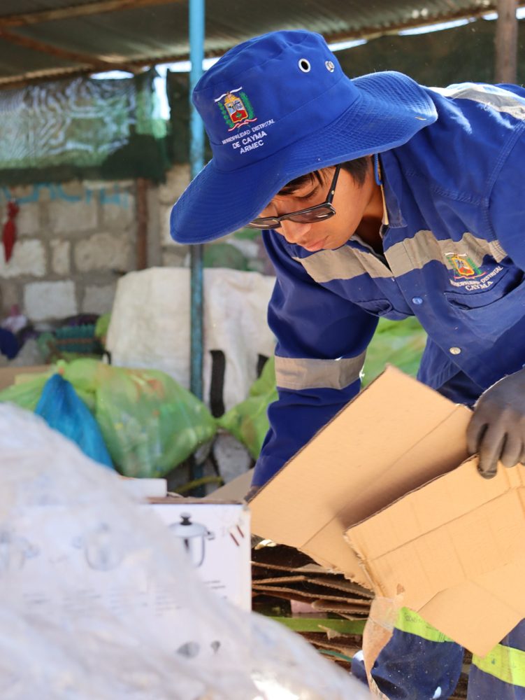 Un joven reciclador con uniforme municipal clasifica cartón