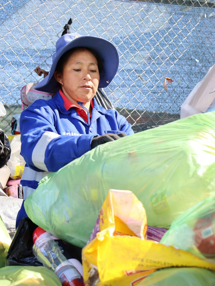 Una recicladora con uniforme azul abre bolsas de material reciclable